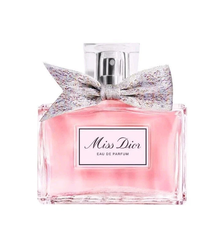 Miss Dior Eau de Parfum bottle with a pink liquid, a silver bow, and a clear cap on a white background.