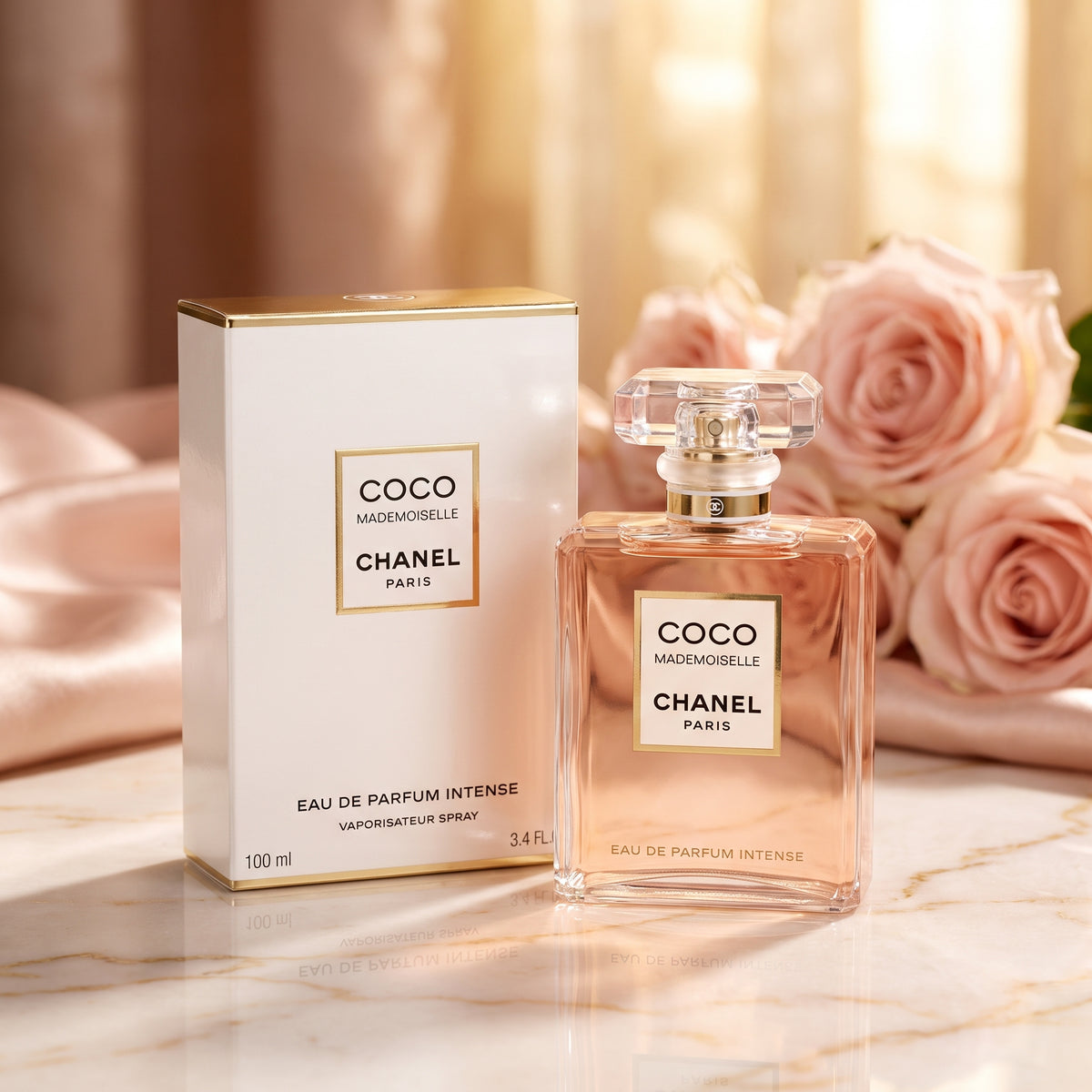 Chanel Coco Mademoiselle Eau de Parfum Intense shown with its white and gold box and the clear glass perfume bottle, styled on a marble surface with pink roses in the background.