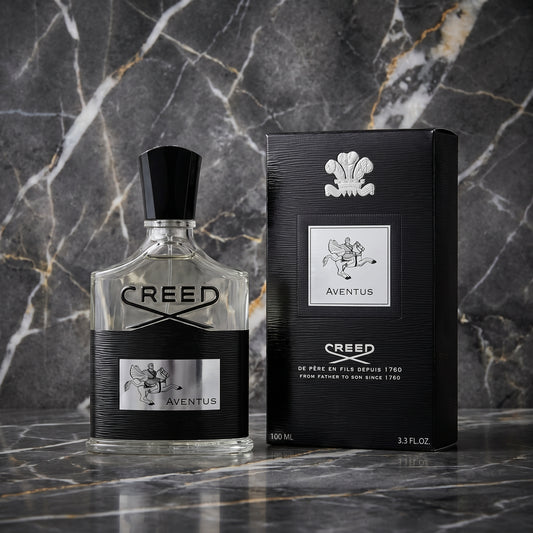 A bottle of Creed Aventus cologne and its black packaging box, both featuring silver and white branding, set against a dark gray marble background.