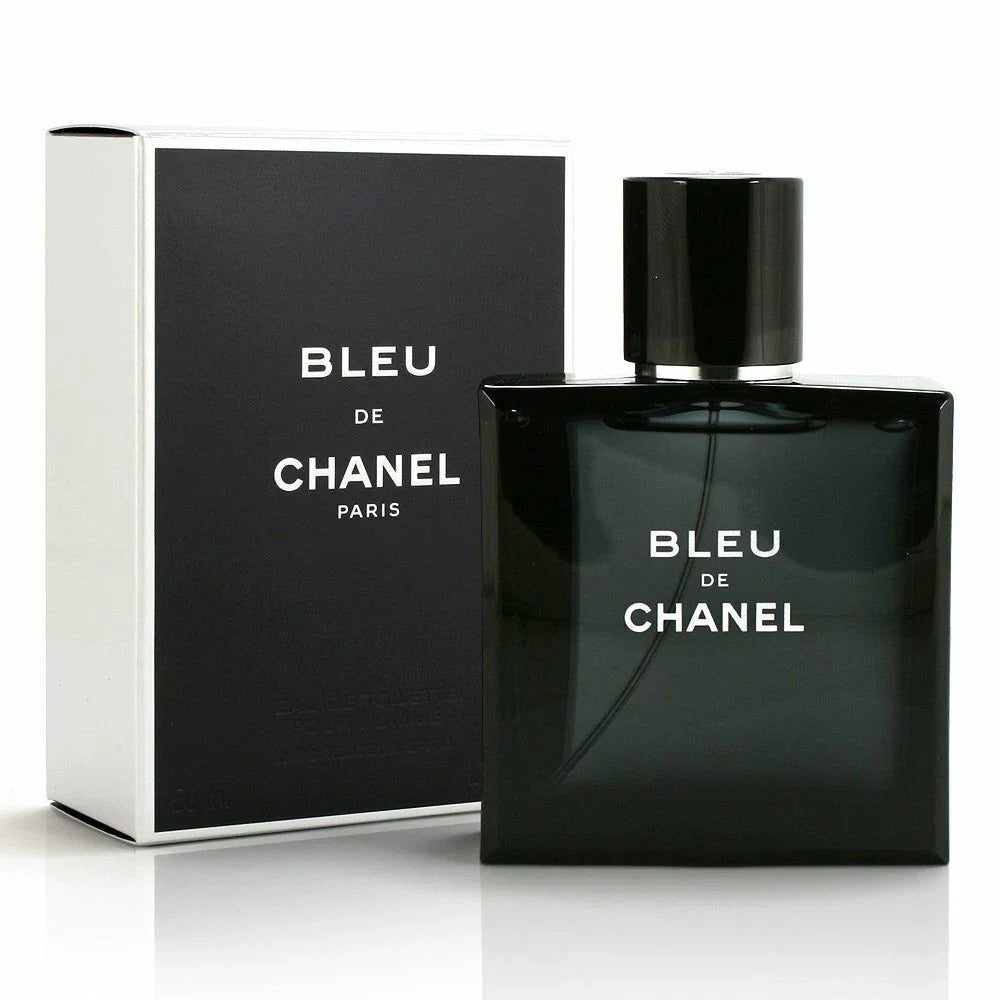 Chanel Bleu de Chanel Eau de Toilette bottle in black glass next to its black and white retail box, on a white reflective surface.