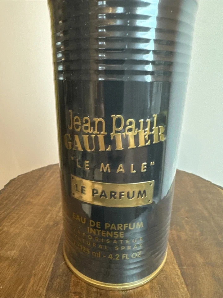 Jean Paul Gaultier Le Male Le Parfum Eau de Parfum spray can, black with gold lettering, sitting on a wooden surface.