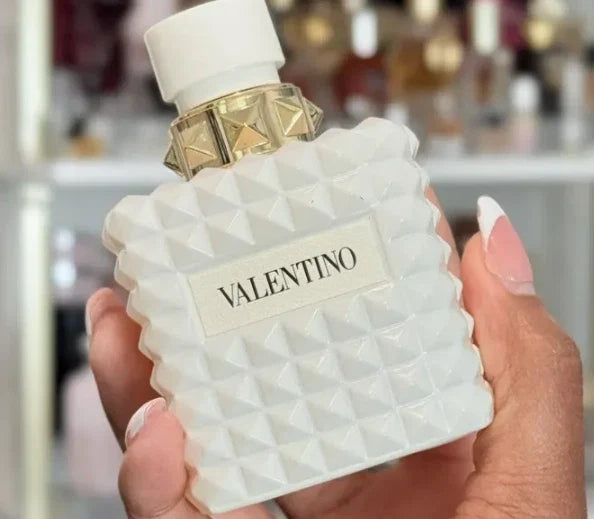 Valentino perfume bottle held in a hand with a blurred background